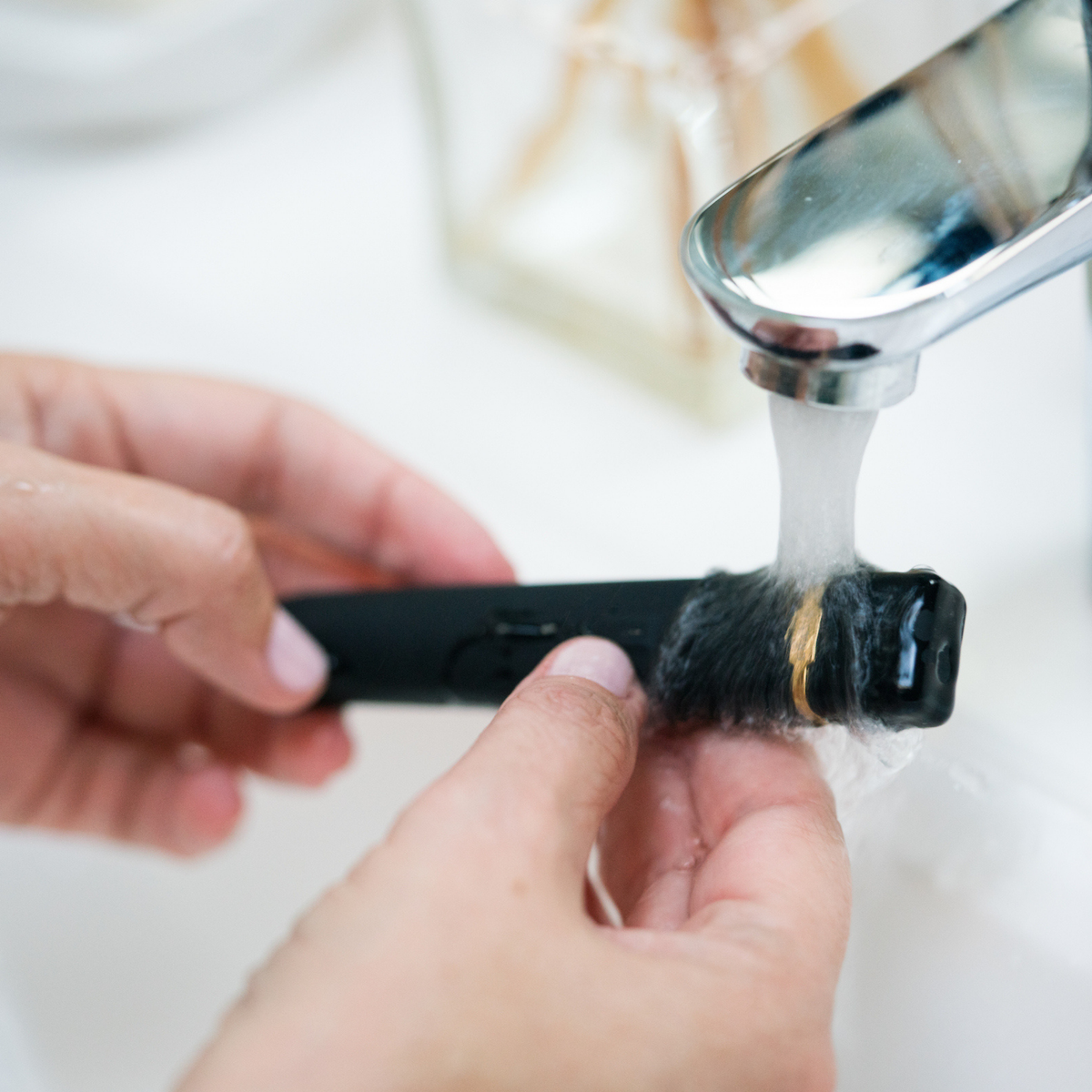 Magnetic USB charging cable attached to a waterproof rechargeable silicone vibrator under running water for easy cleaning