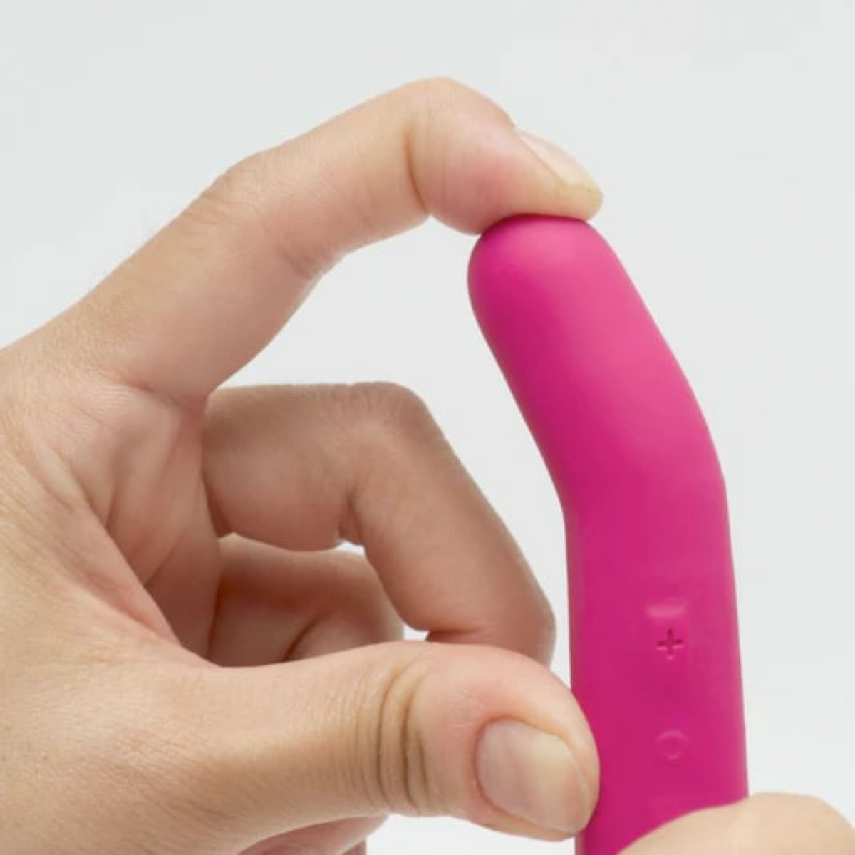 Hand holding a compact pink silicone vibrator showing ergonomic curved design